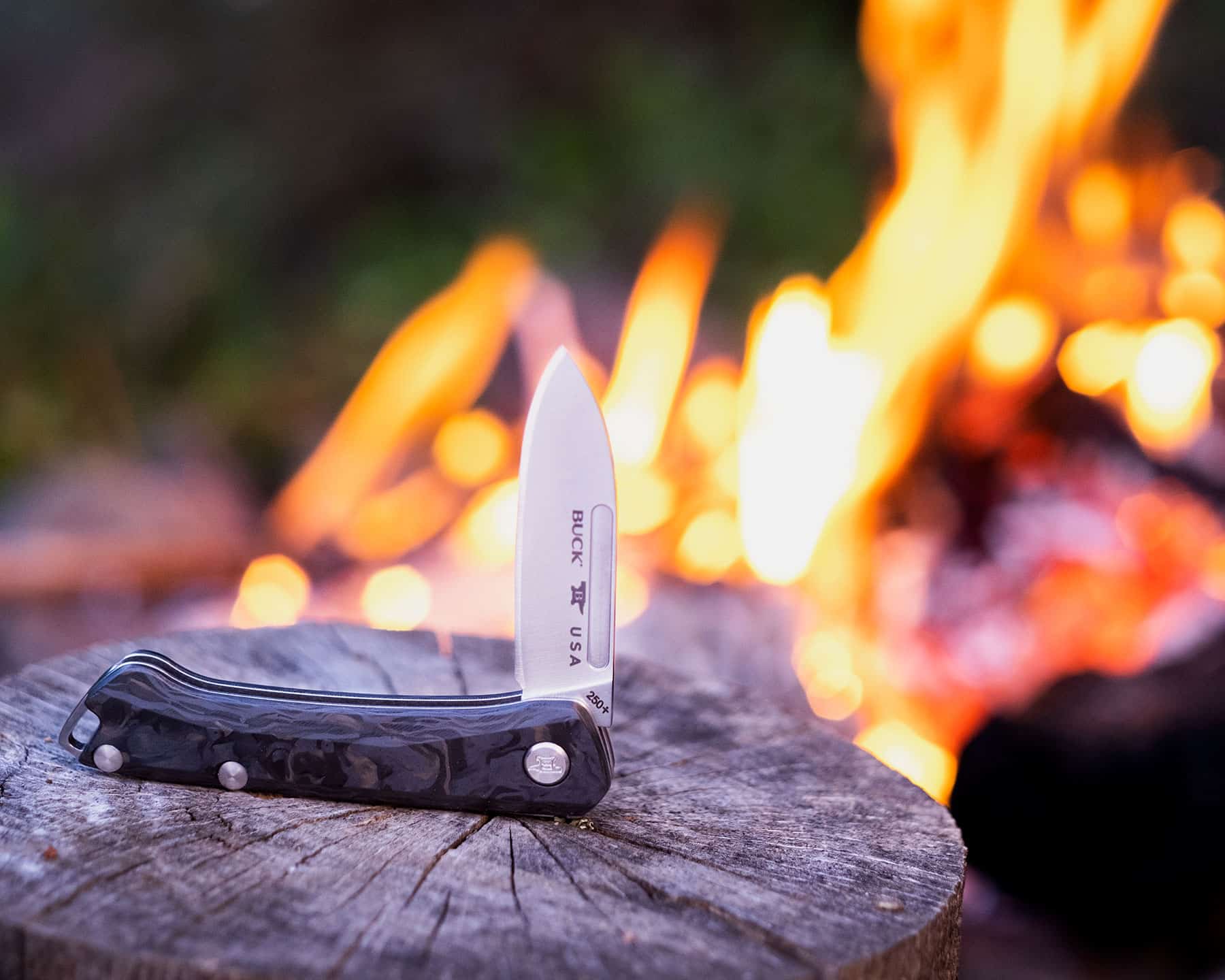 The Buck Saunter is a practical pocket knife for both the office or the outdoors. It is shown here next to a campfire.
