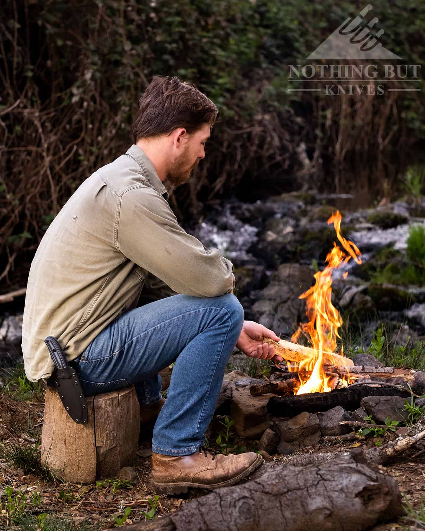 A man sitting by a campfire with the Off-Grid Ridgeback in it's sheath on his belt to show what a great camping knife it is.