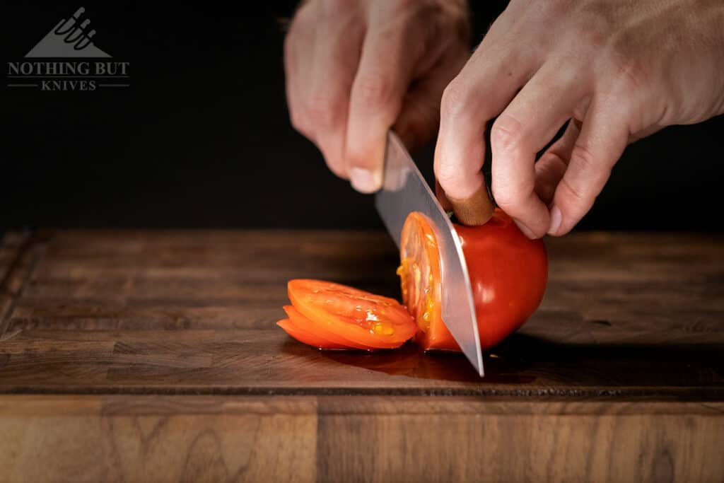 A close-up of a Tactile Santoku Knife slicing through a tomato to show it's great edge.