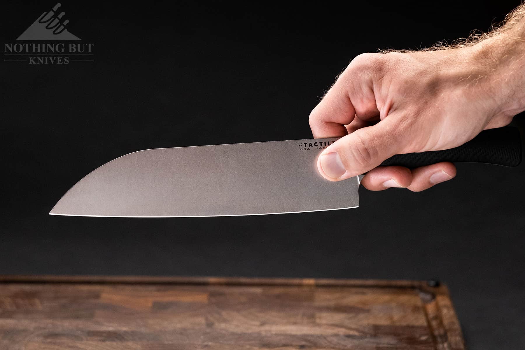 A close-up of a person's hand holding the Tactile Chef Knife in a pinch grip to show handle ergonomics. 