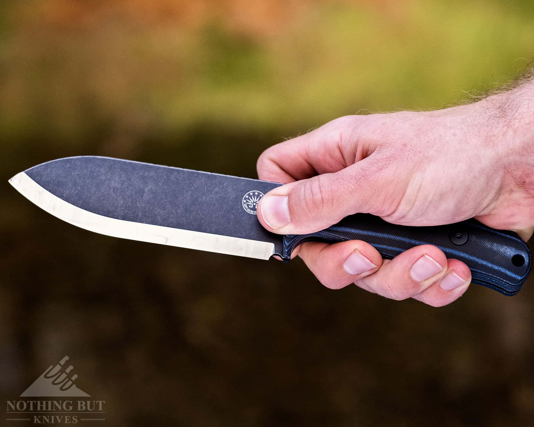 A close-up of a person's hand holding the Off-Grid Ridgeback in a pinch grip. 