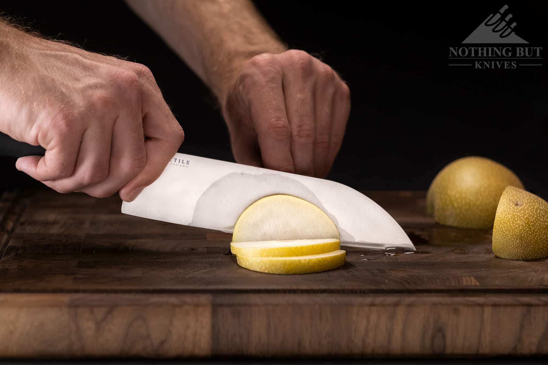 Close-up image of a the Tactile chef knife being used to slice an Asian pear to show its slicing ability.