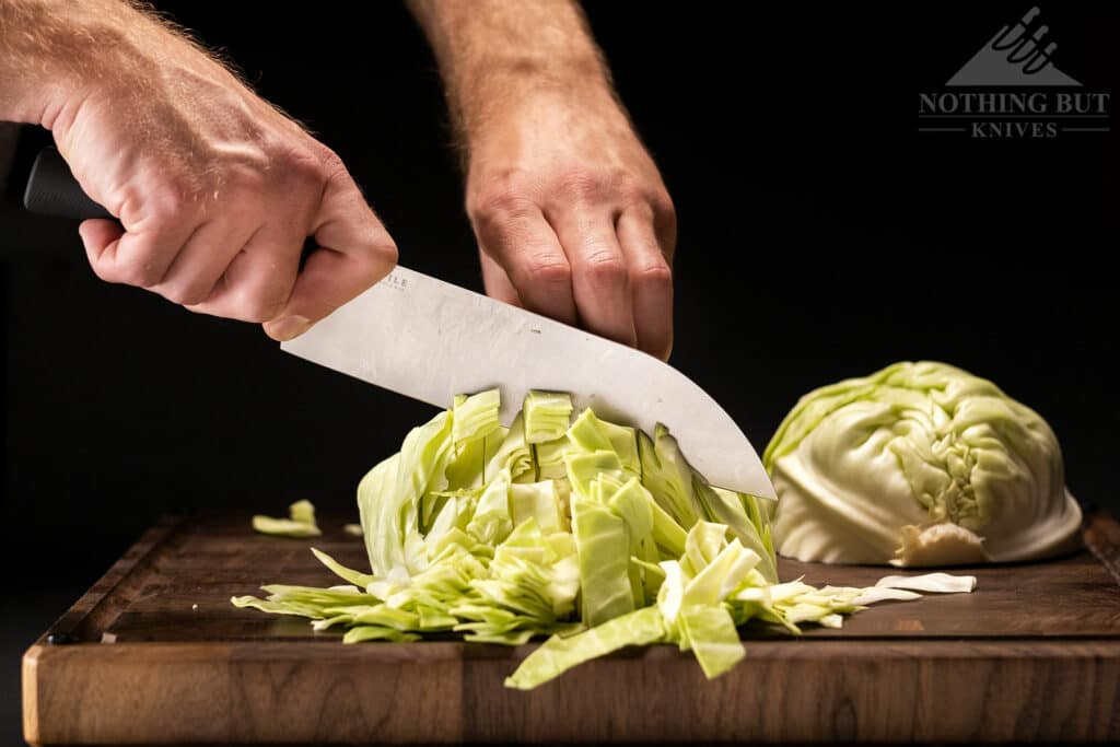 The relatively thin blade of the Tactile 8 inch Chef Knife cutting through cabbage. 