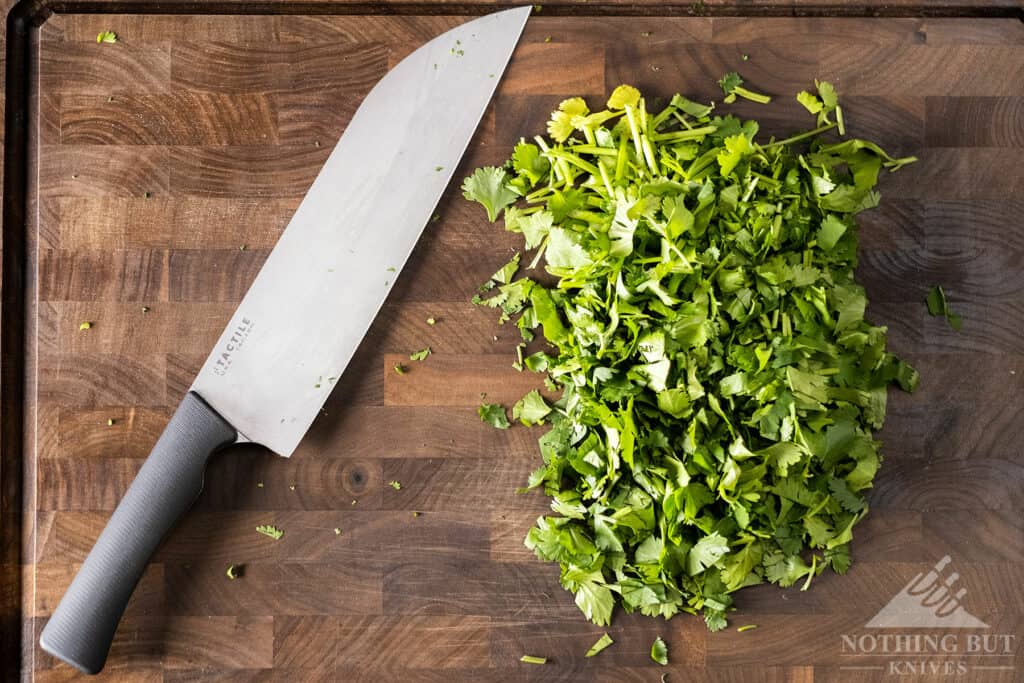 The American made Tactile Santoku Chef Knife next to a pile of chopped cilantro.