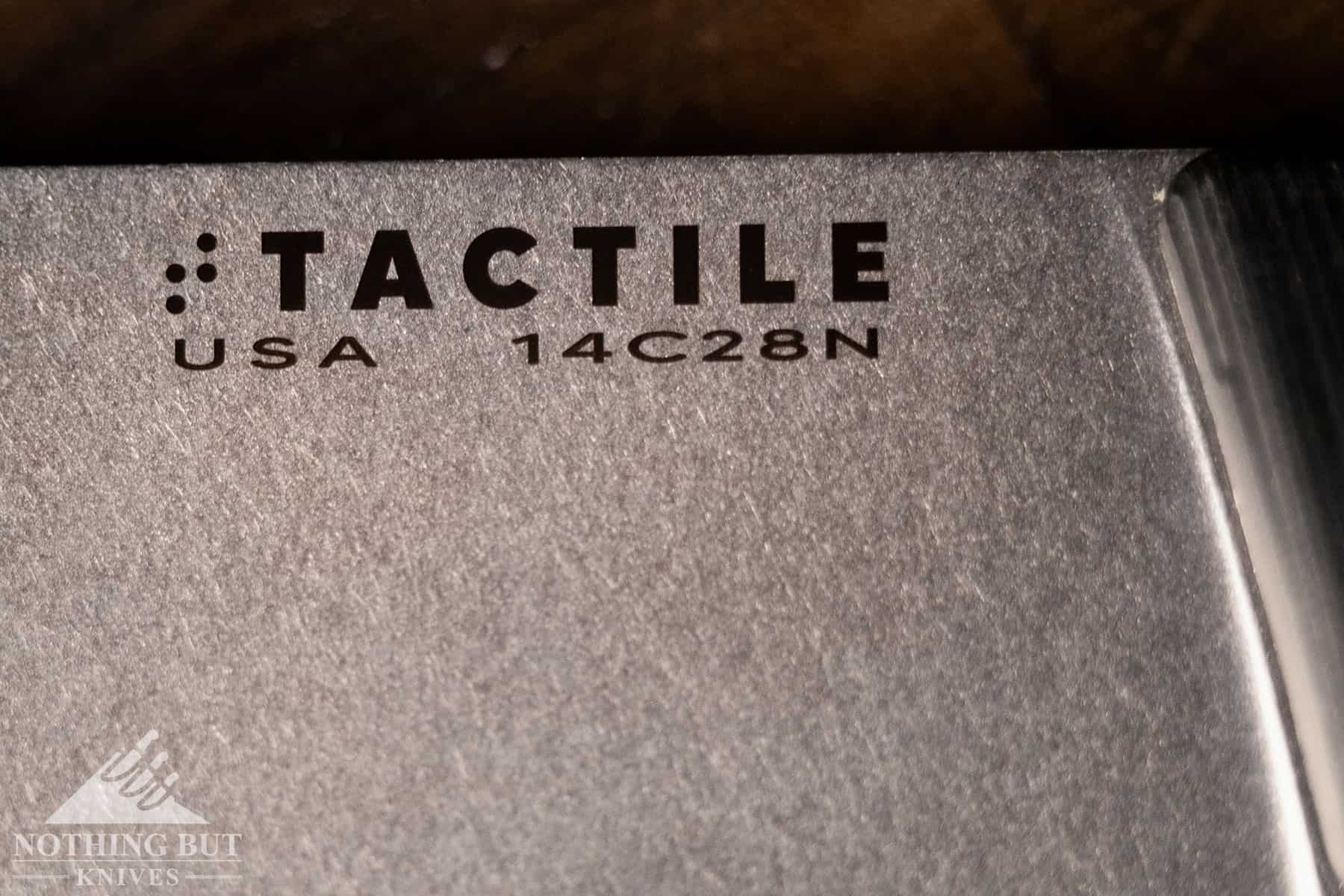 Macro shot of the Tactile logo and steel branding on the side of the chef knife blade.