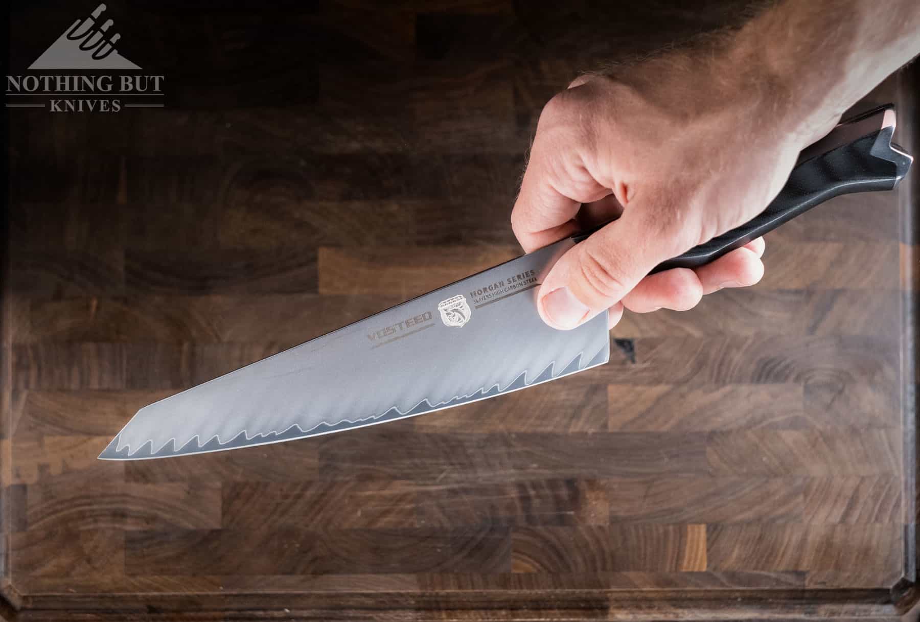 A close-up of a person's hand holding the Vosteed Morgan chef knife in a pinch grip. 