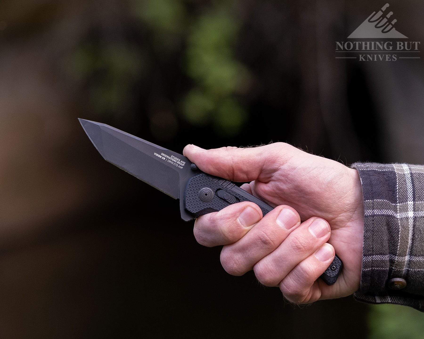 A person's hand holding the SOG Vision XR to show the knife's ergonomic handle in use.