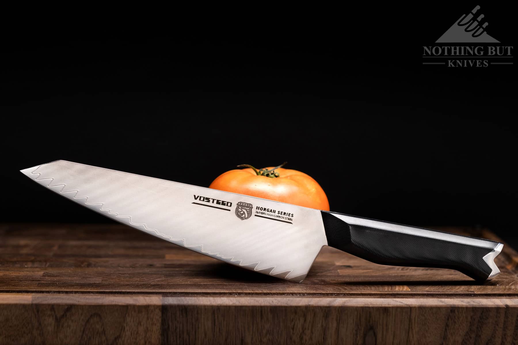 The Vosteed Morgan chef knife offers good  performance for the money. It is shown here on a wood cutting board next to a tomato.