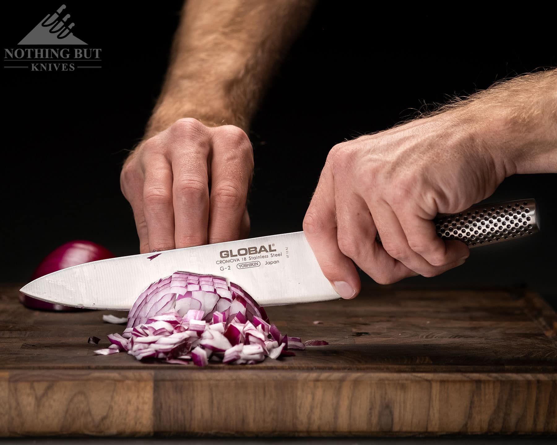 A Global chef knife being used to dice onions to show the knife's blade retention.