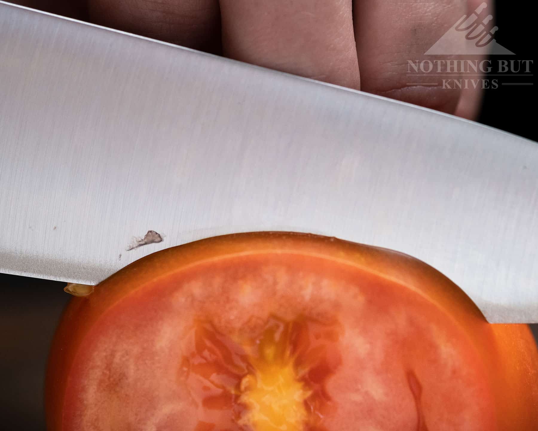 Global G-2 8 Inch Chef'S Knife Review - Image 2 A close-up image of the Global G2 chef knife slicing through a tomato.