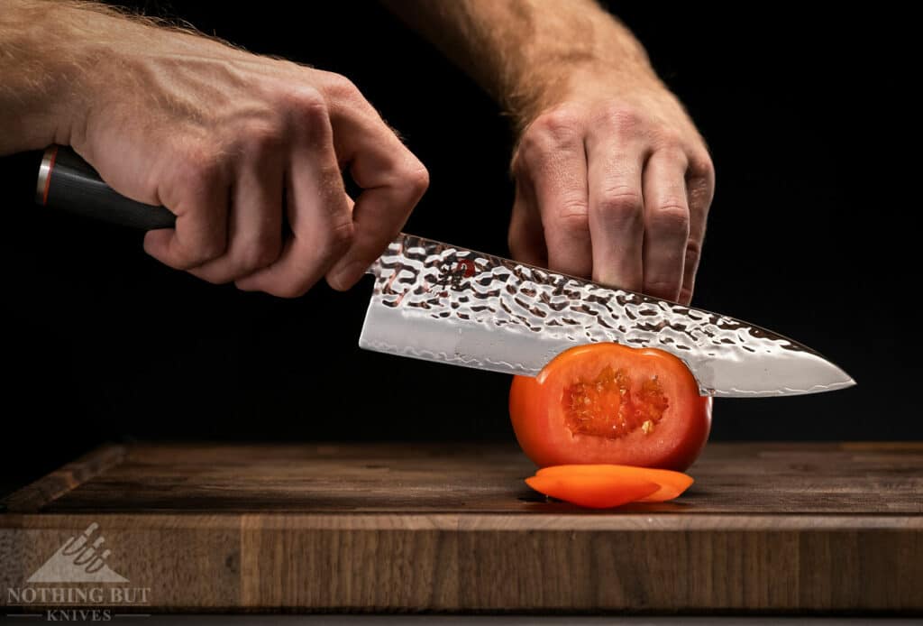 Miyabi 8 inch chef knife slicing a tomato.