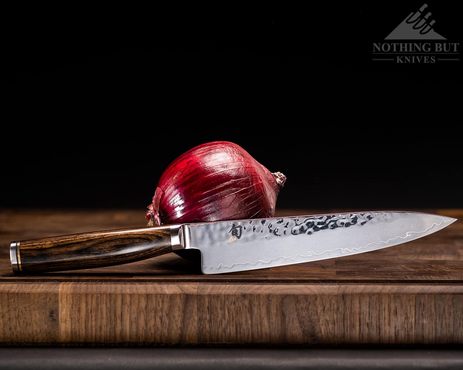 The excellent Shun Premier utility knife is shown here on a cutting board with a red onion. 