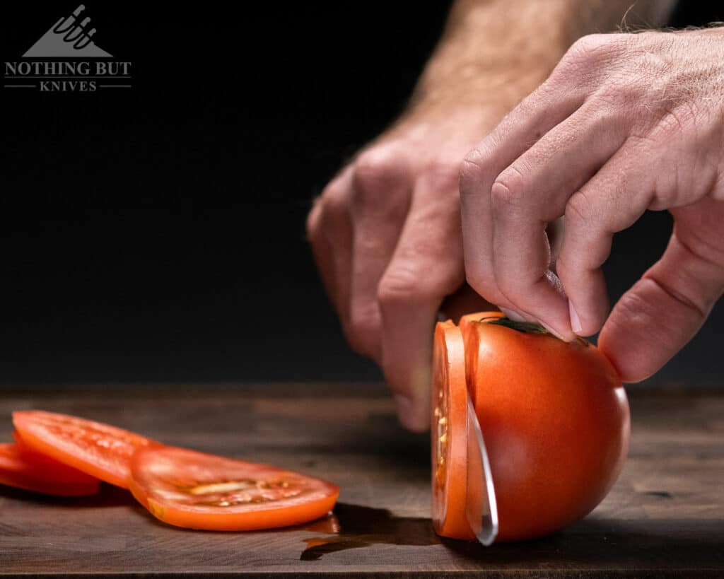 A close-up of the convex grind of the Global G2 chef knife slicing through a tomato. 