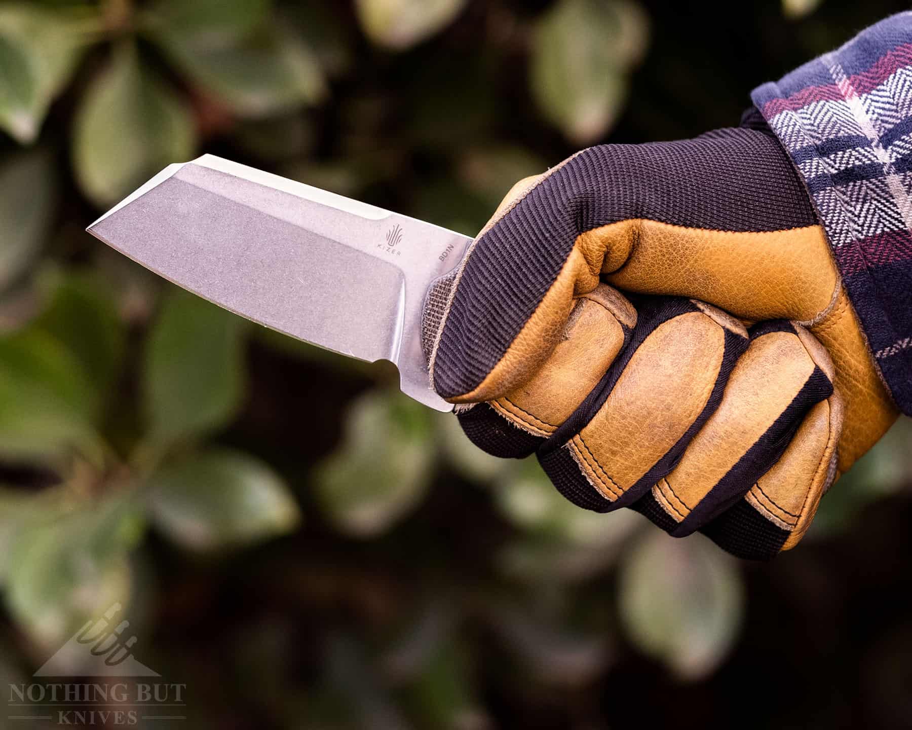 A close-up of a person's gloves hand holding a hard-use folding knife.