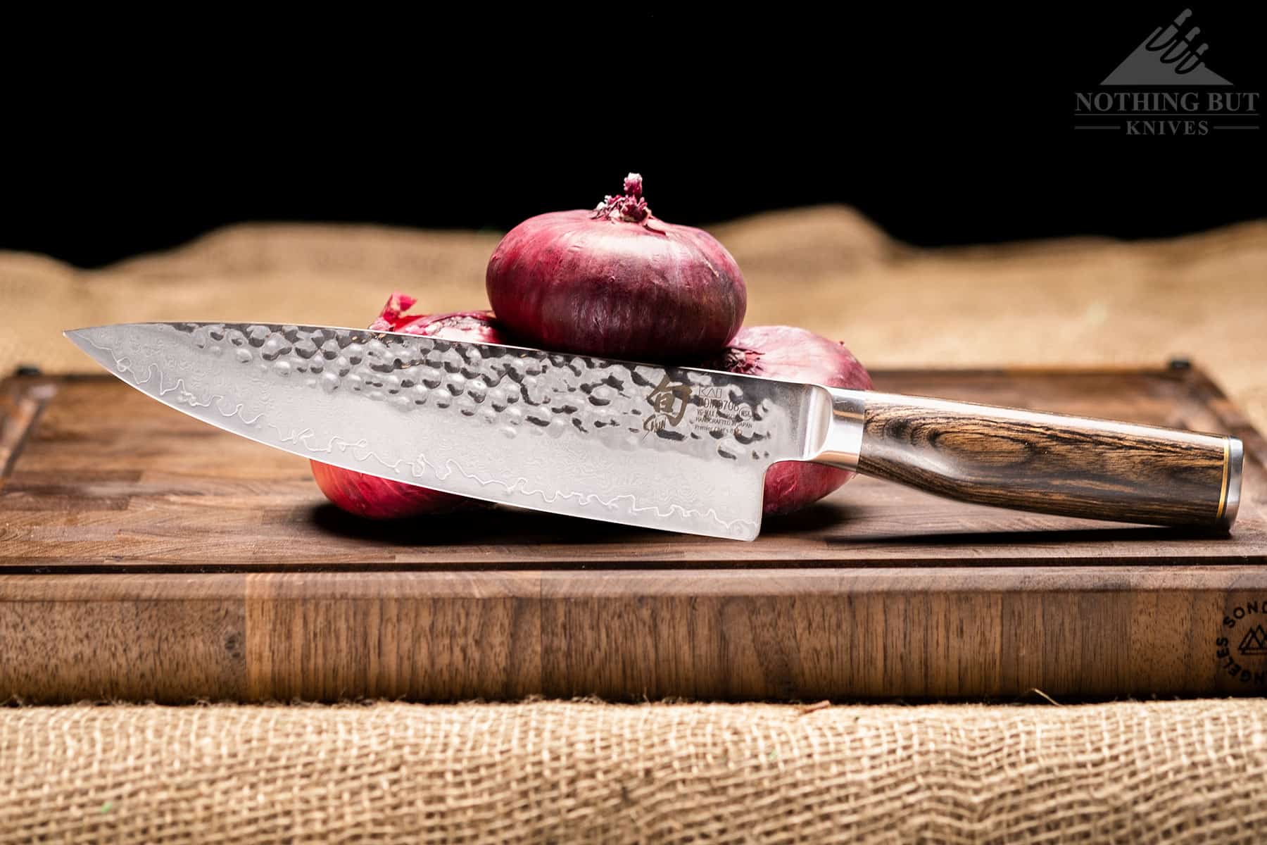 Shun Premier Chef'S Knife Review - Image 1 This image features the 8 inch Shun premier chef knife with a stack of onions on a cutting board to show scale.