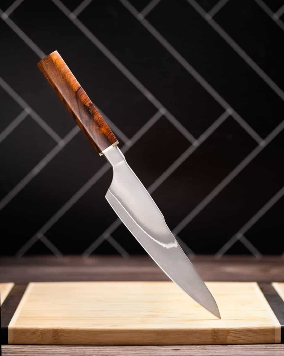 Oishya Sakai Kyuba Gyuto Chef'S Knife Review - Image 10 The Xin Cutlery chef knife suspended over a cutting board.