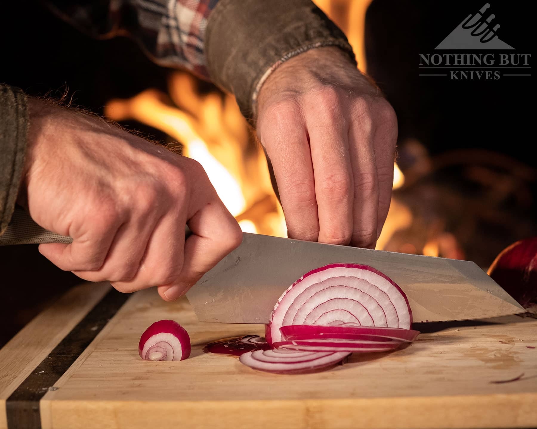 The Overland che knife is a good option for overlanding or camping trips. Here it is being used to slice up an onion next to a campfire on a camping trip.