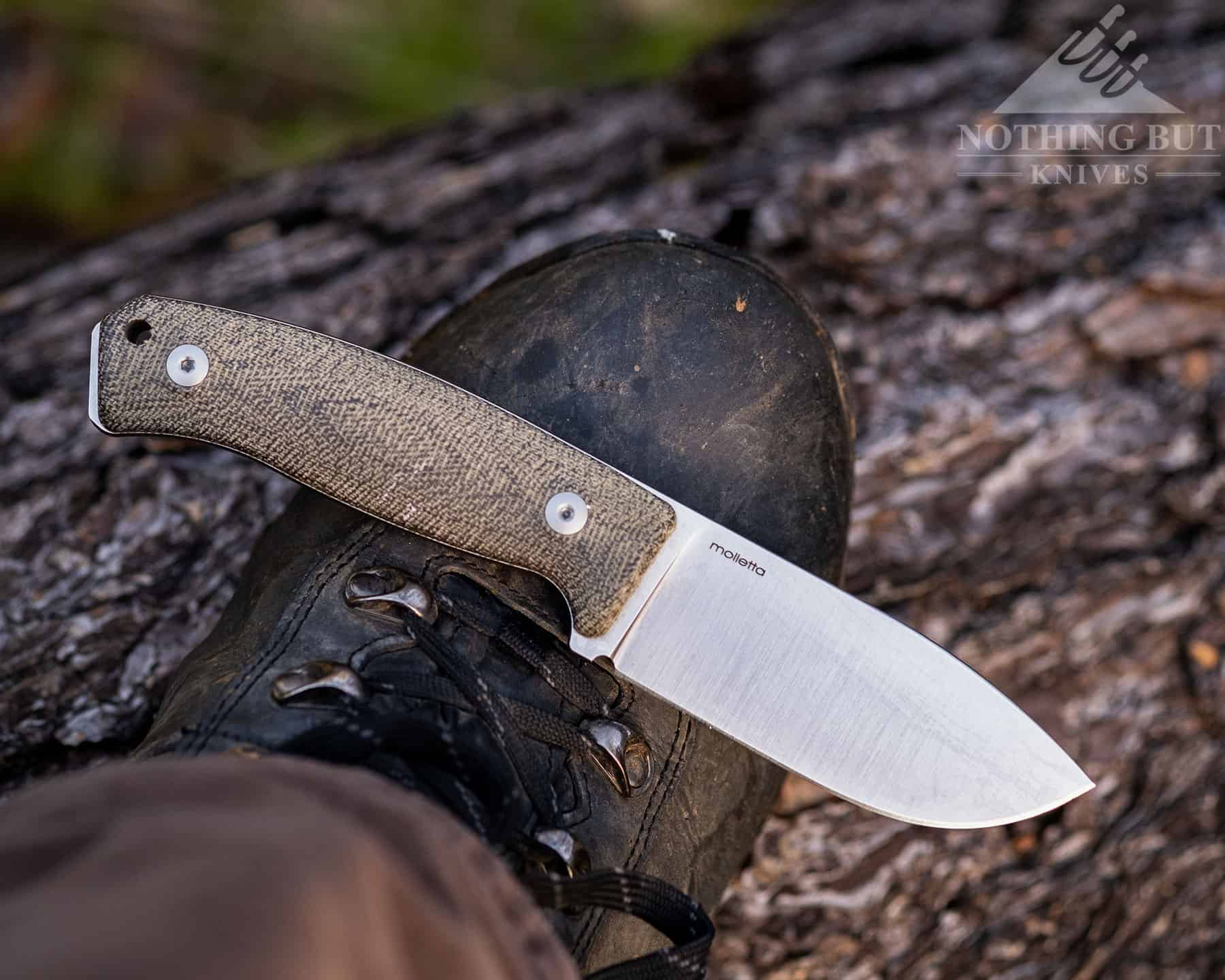 Lionsteel M2M Review - Image 20 The M2M laid acros a person's right boot with the blade pointing to the right.