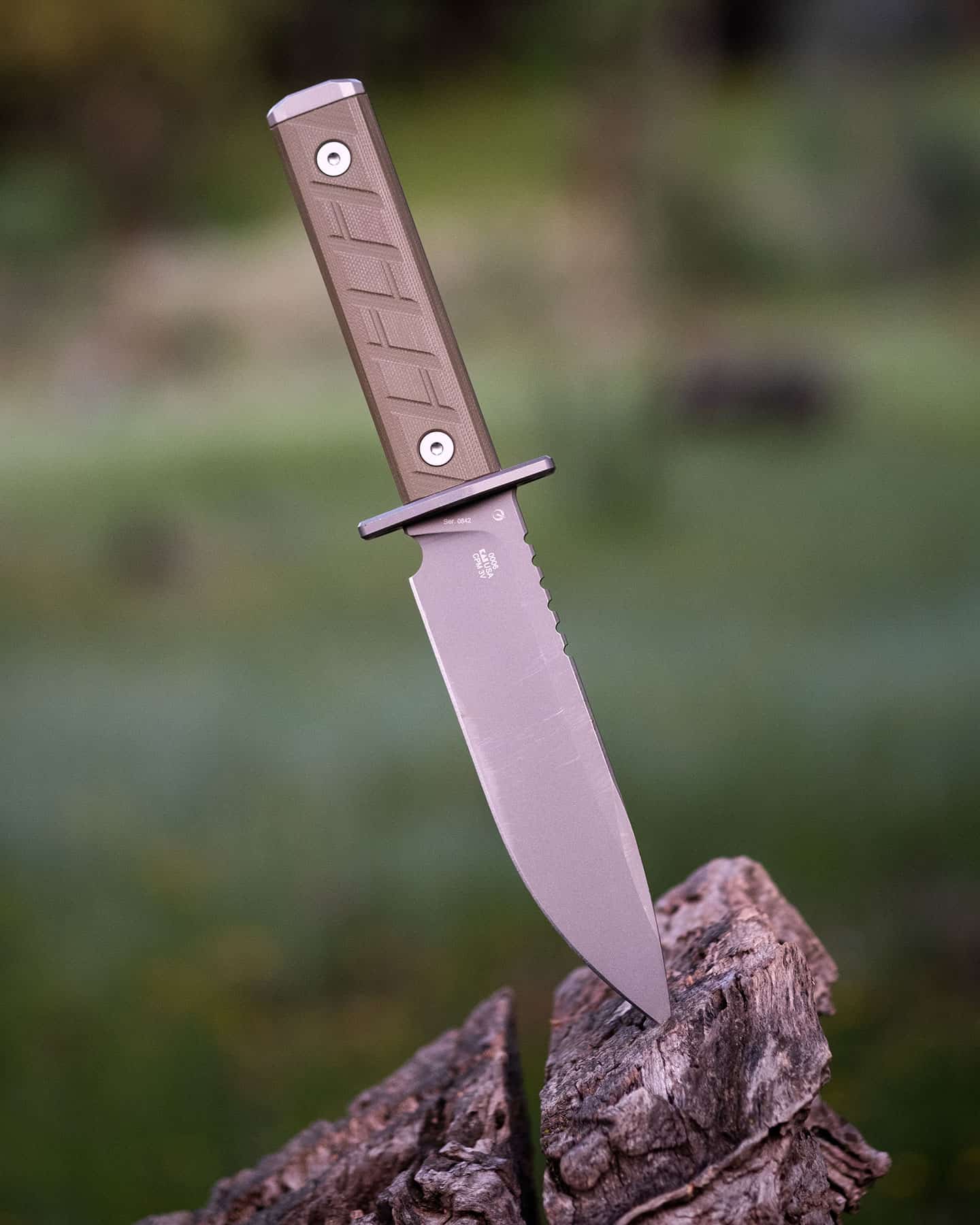 The Zero Tolerance 0006 fixed blade knife shown here with its blade tip stuck in the top of a tree sump in a green field.