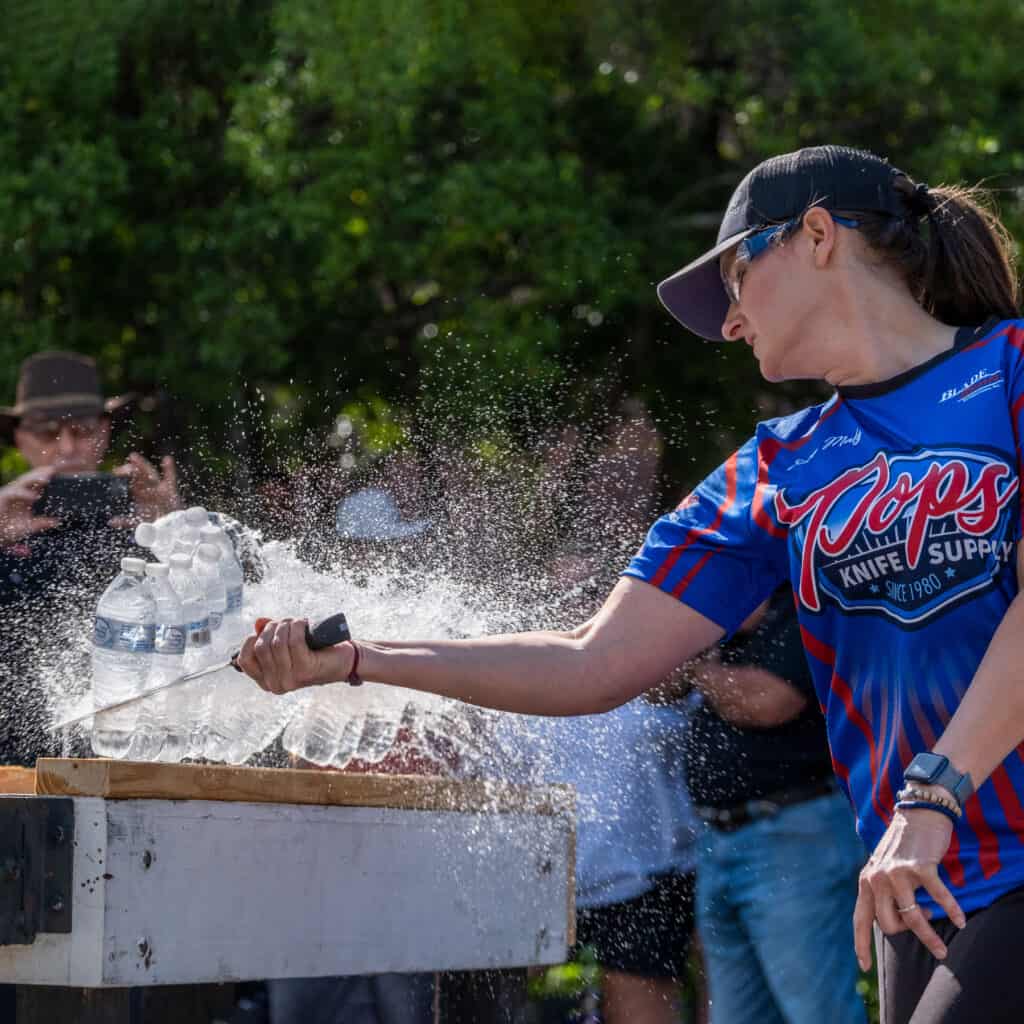 Sara Maly of BladeSports International slicing ten bottles during the cutting competion at Blade Show 2023.