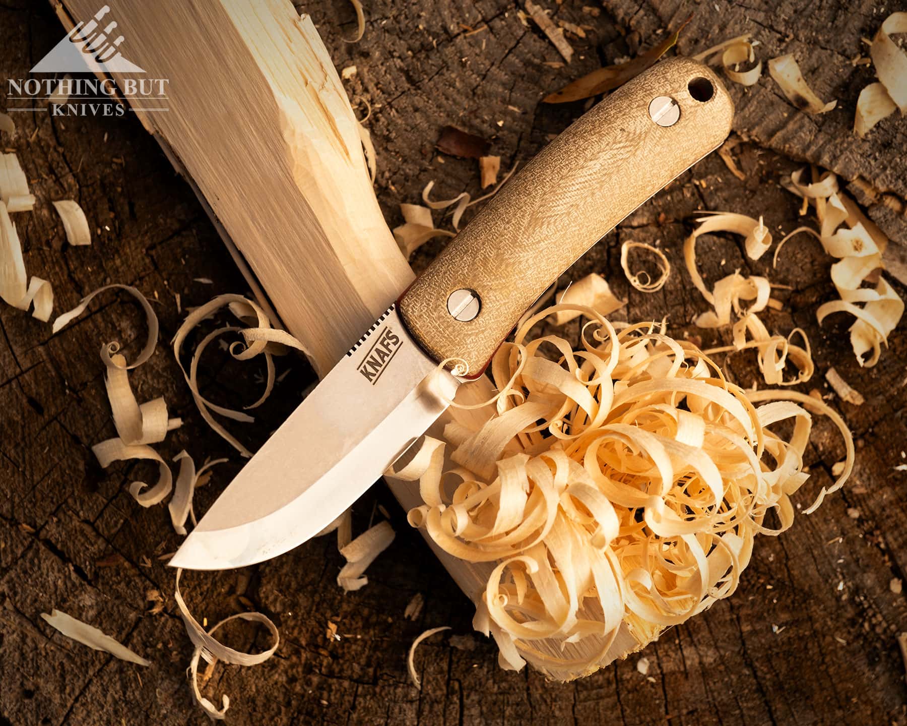 An overhead view of the Knafs Lulu knife on top of a feather stick it was used to carve. 