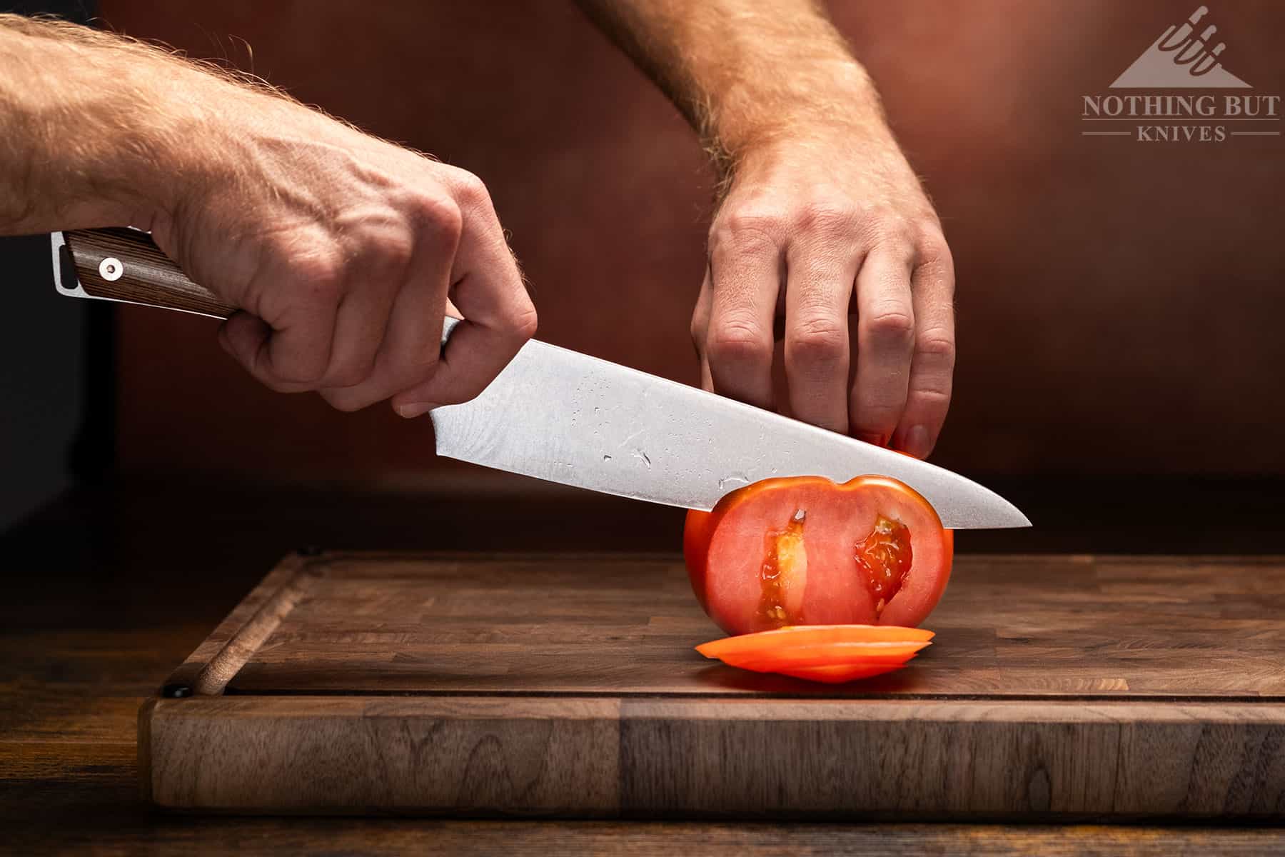 Shun Kanso Chef'S Knife Review - Image 5 The Kanso's polished edge cutting a slice off a tomato.