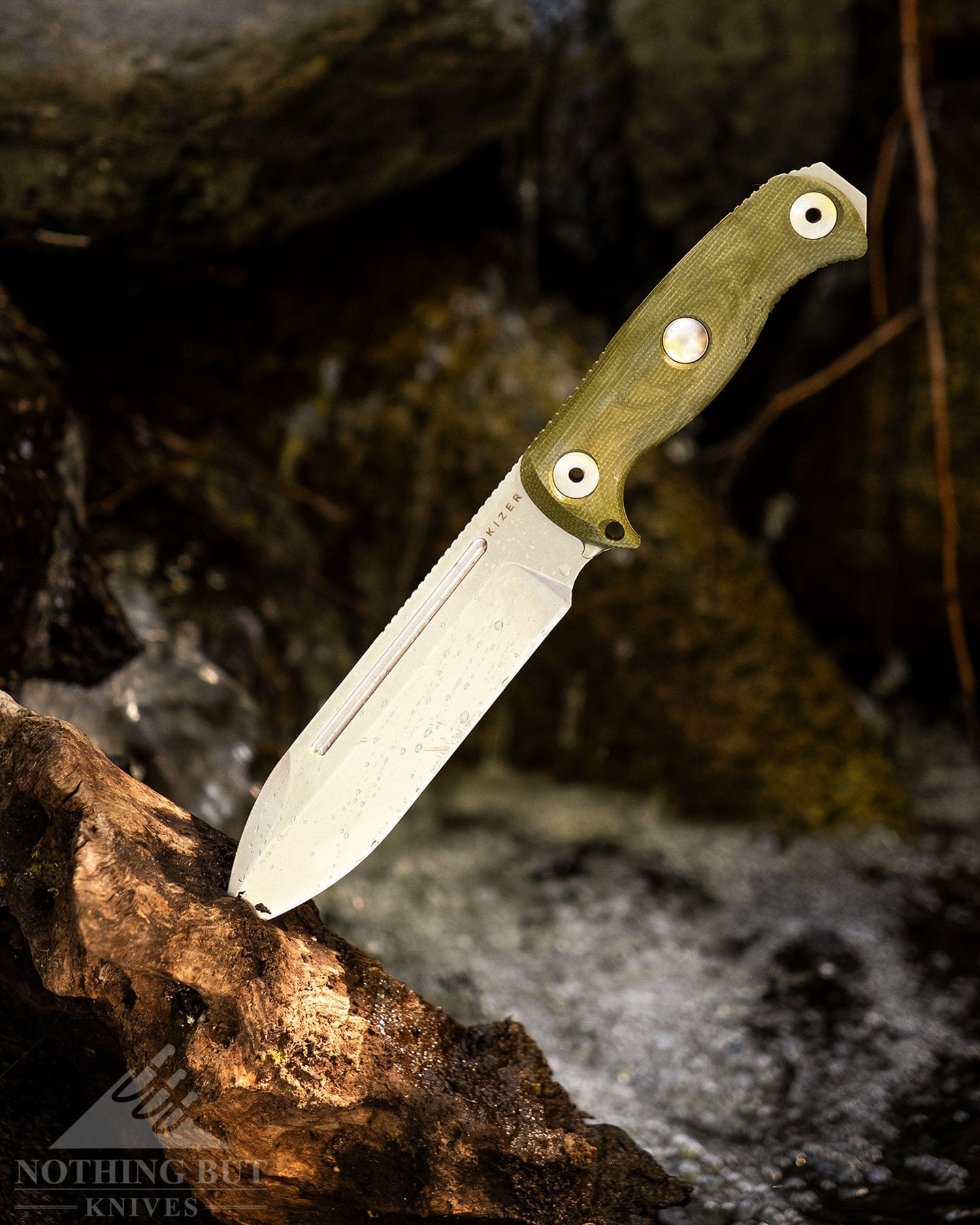 Kizer Fixed Blade Knife Guide - Image 3 The Kizer Drop Bear Fix 7 survival knife sticking out of a log next to a mountain creek.