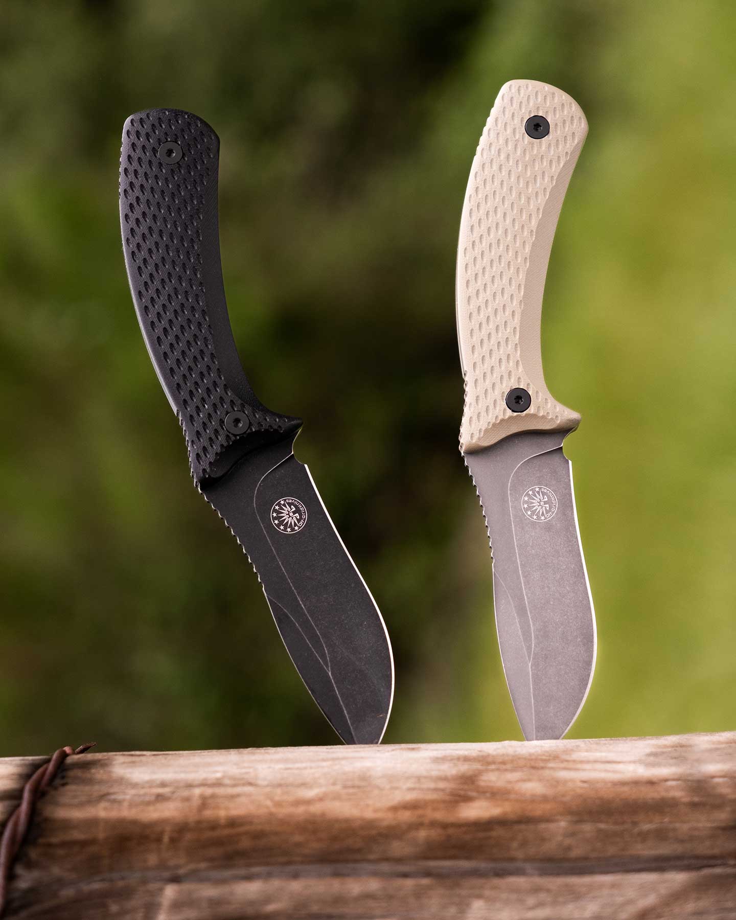 Both color versions of the Off-Grid Sidekick fixed blade knife next to each other on a weathered fencepost in a field.