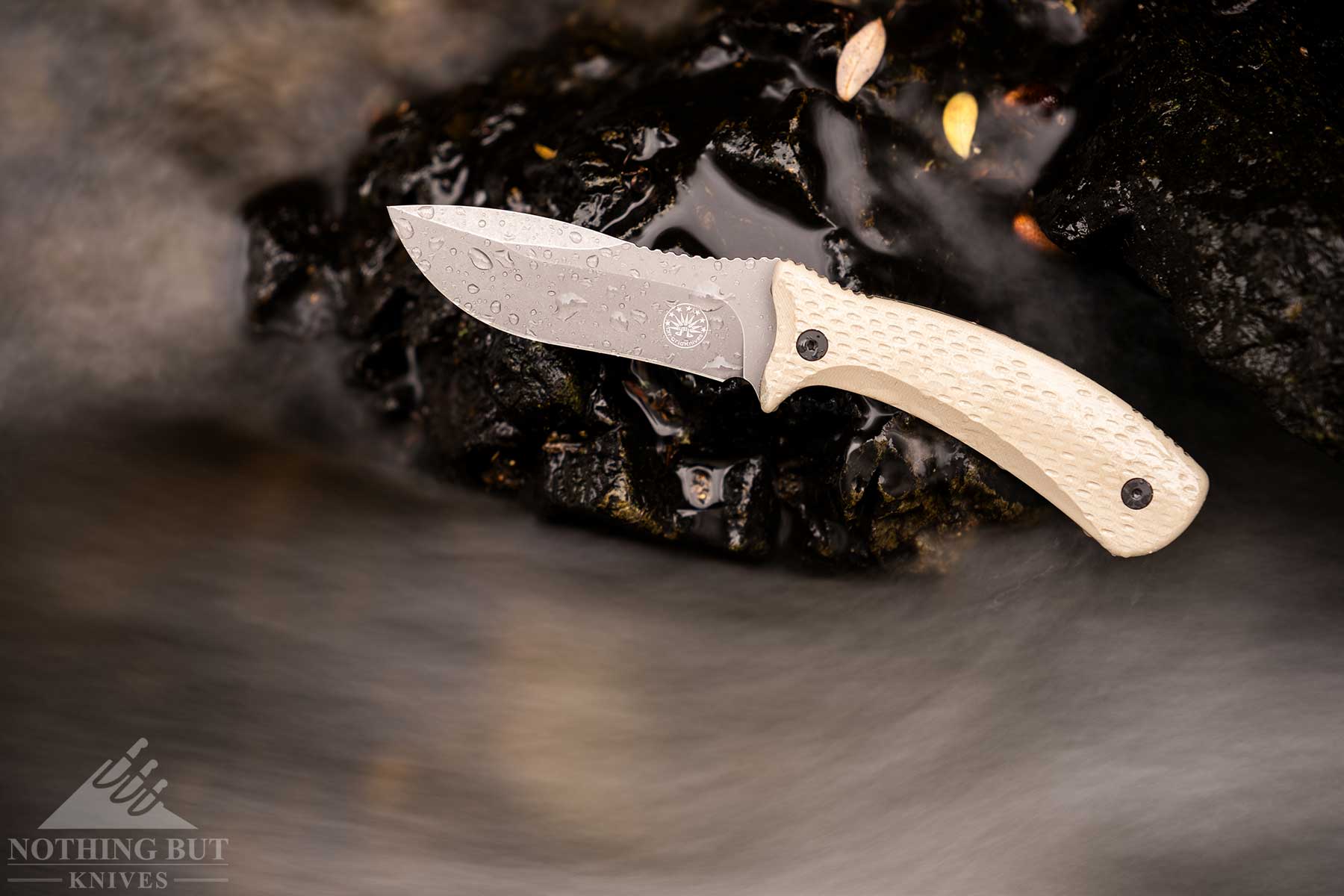 Off-Grid Sidekick Review - Image 2 An overhead view of the Coyote version of the Off-Grid Sidekick fixed blade on top of a rock next to a stream.