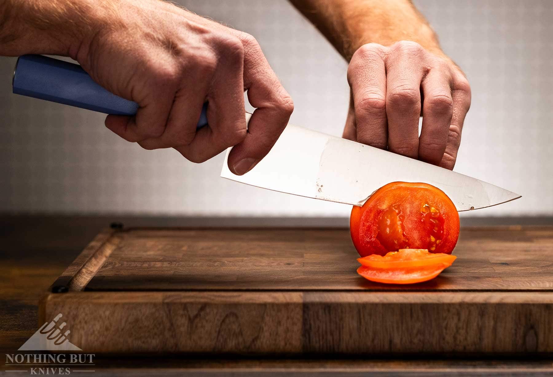 Review Of The Butterfork 4 Piece Kitchen Knife Set - Image 3 A close-up of a Butterfork chef knife being used to slice a tomato.