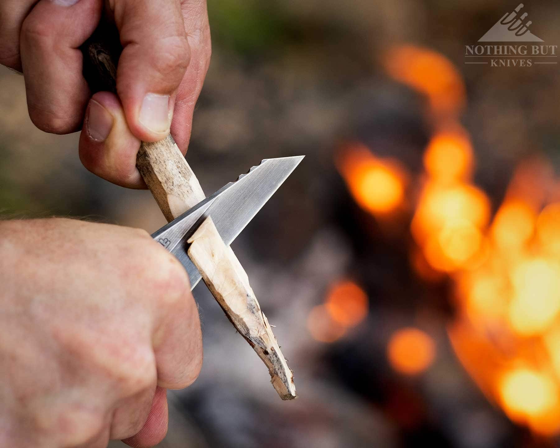 T.kell Wharnedc Review - Image 2 An overhead view of the TKell WharnEDC being used to carve a stick next to a campfire.