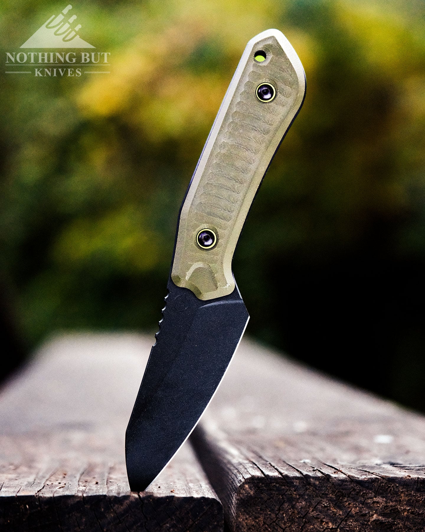 Our Favorite Fixed Blade Edc Knives And How To Carry Them - Image 22 Schwarz Knives Overland X shown here with its black blade sticking out of a picnic bench in the forest.