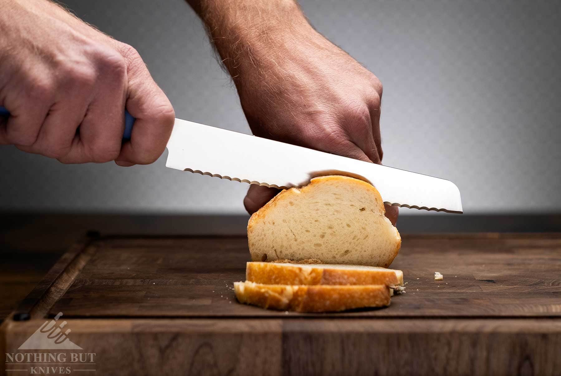 Review Of The Butterfork 4 Piece Kitchen Knife Set - Image 5 The Butterfork bread knife being used to slice a loaf of French bread on a wood cutting board.