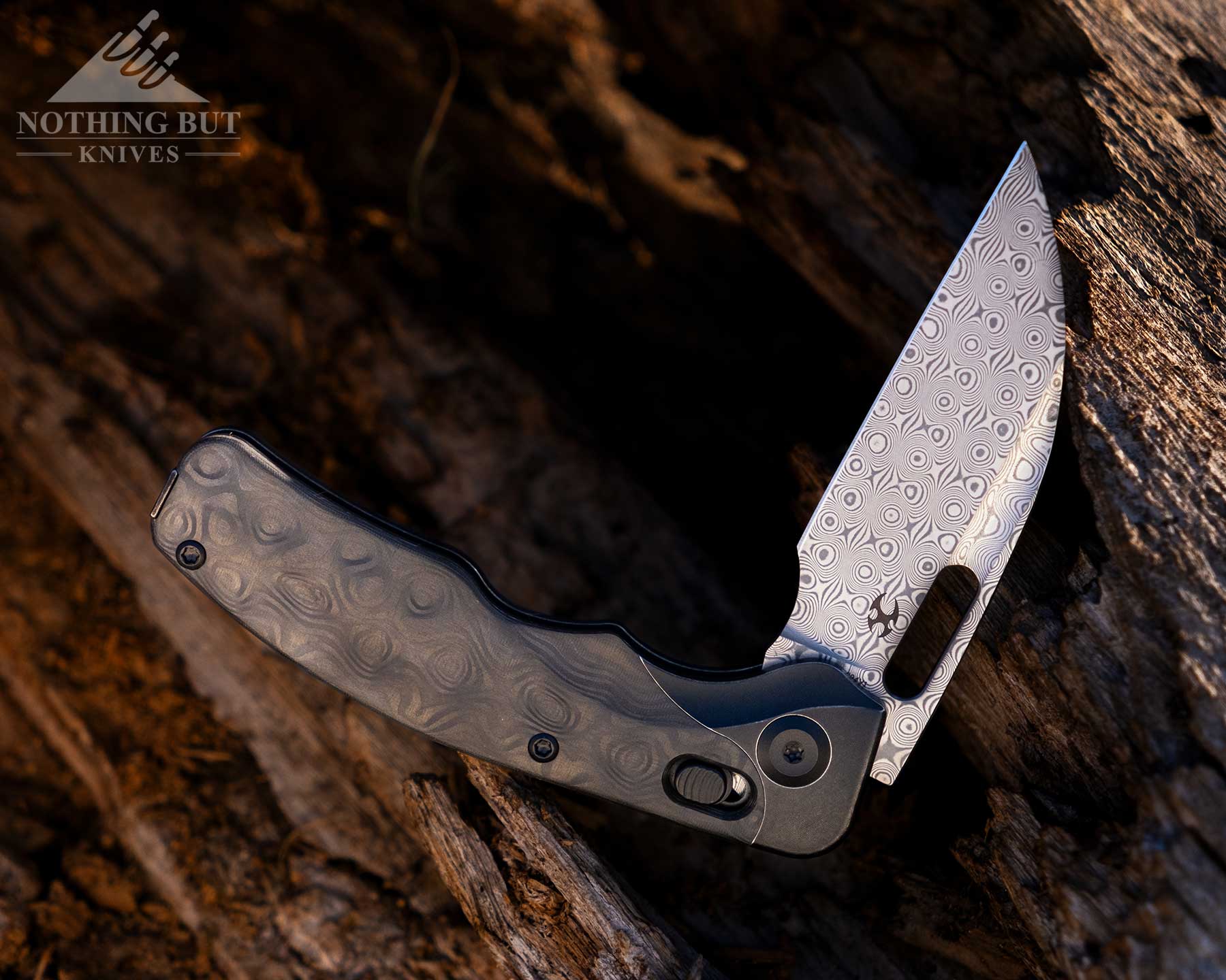 Kansept Vivid Review - Image 2 The Kansept Vivid with its blade in the half open position balanced on the edge of a large log.