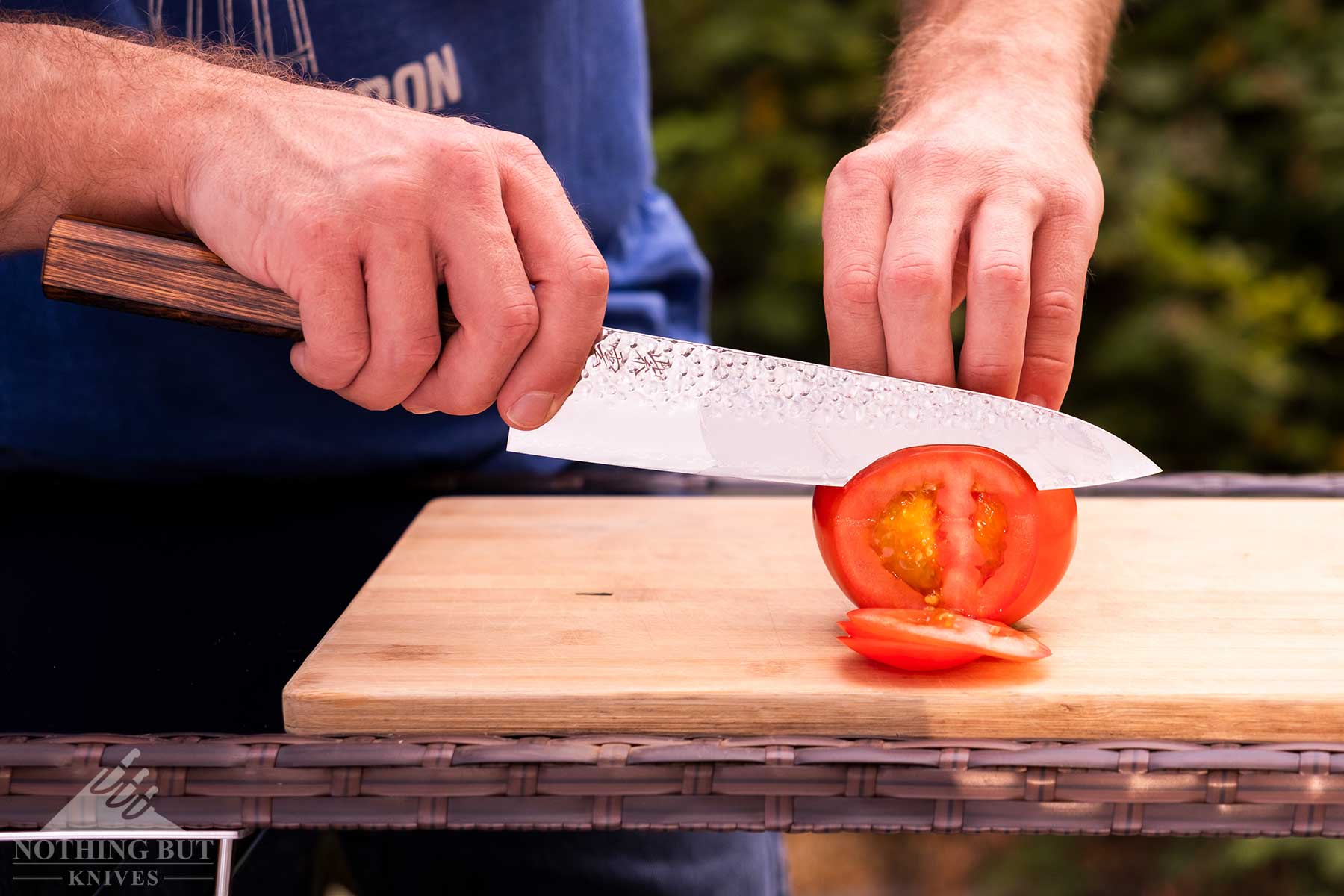 Demko Gyuto Chef Knife Review - Image 5 A close-up of the Demko chef knife slicing through a tomato on a bamboo cutting board.