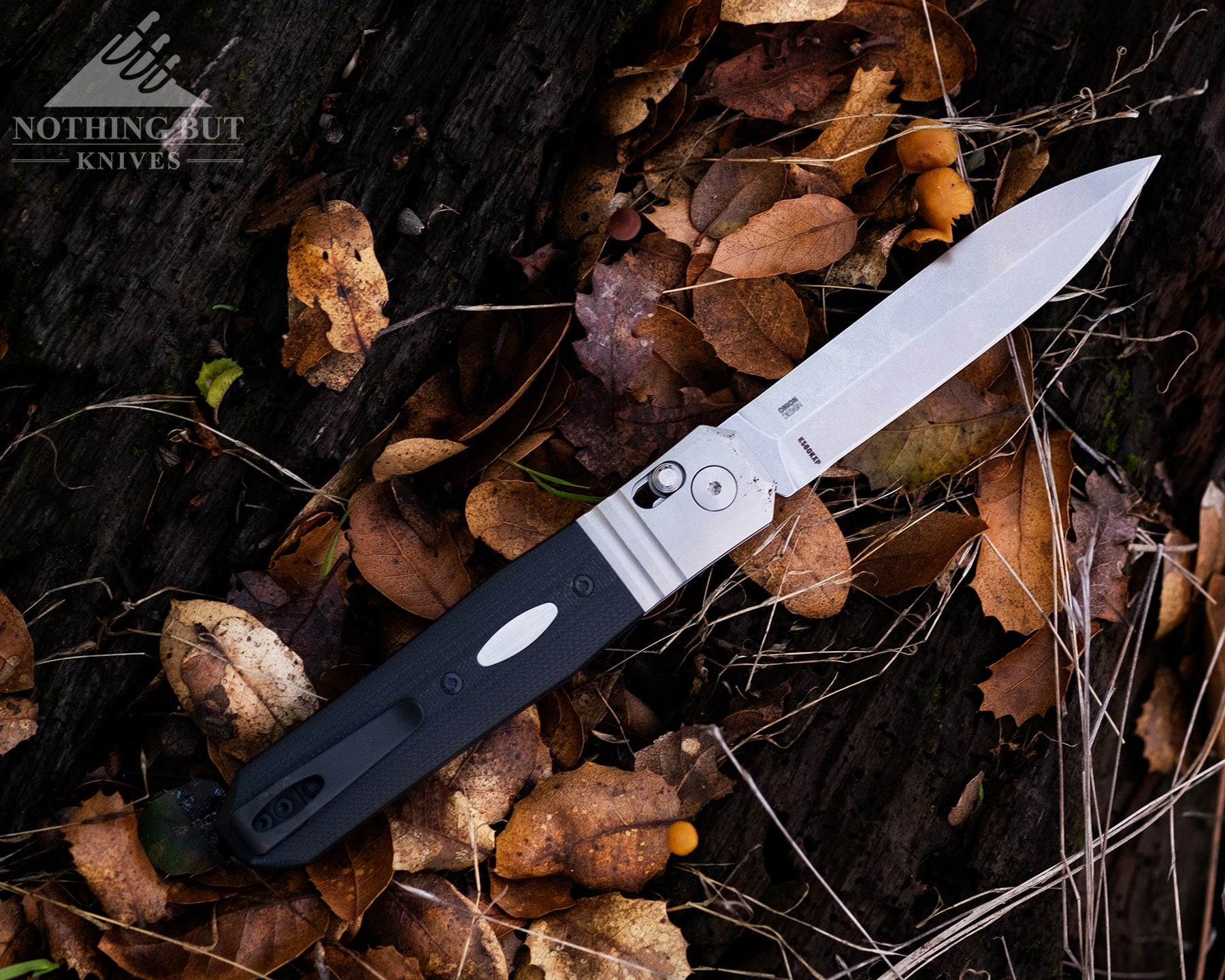 An overhead view of the CRKT Redemption folding knife shown here with its blade in the open position on a pile of oak leaves.