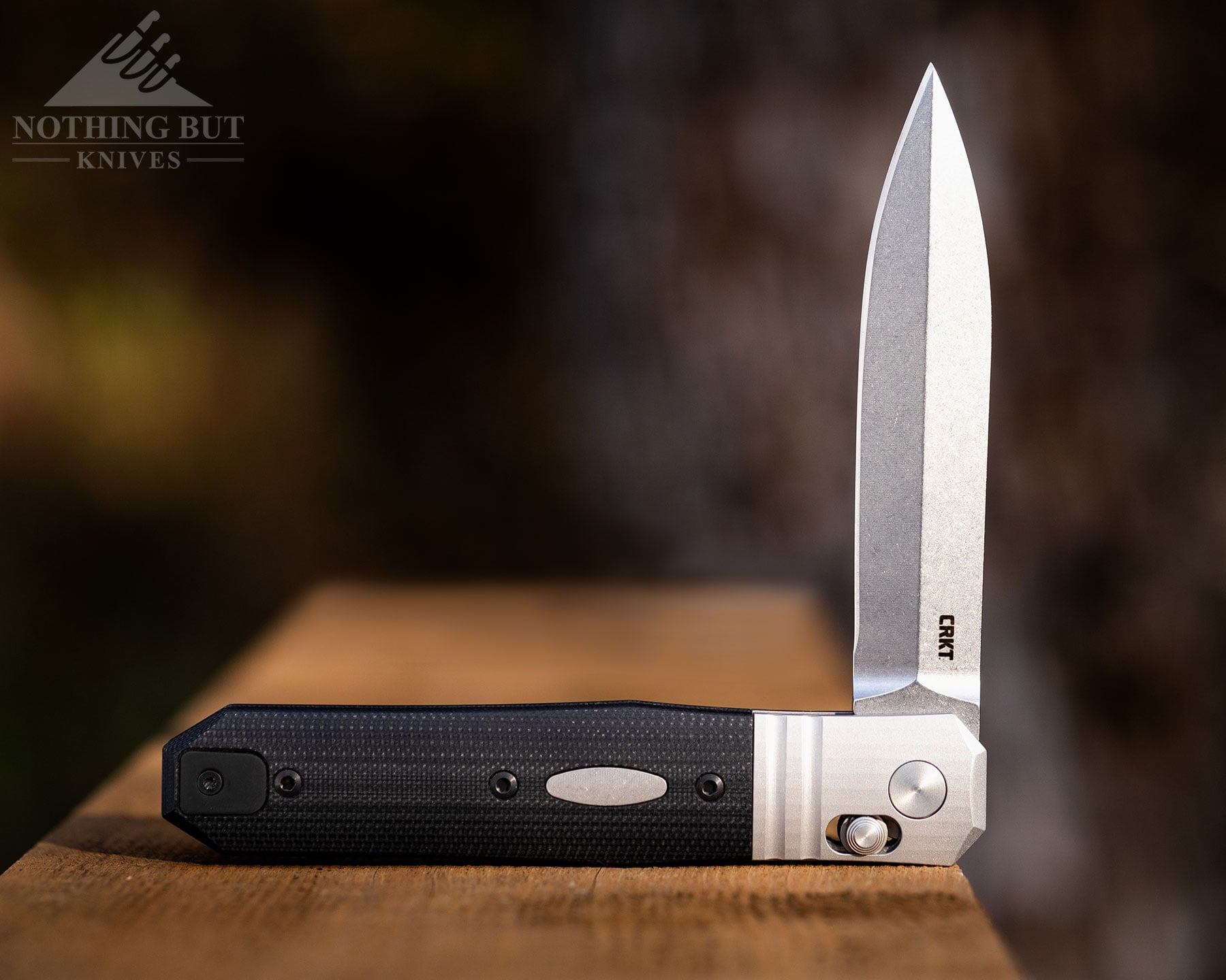The CRKT Redemption shown here with its blade in the half open position on top of a wooden bridge guard rail. 