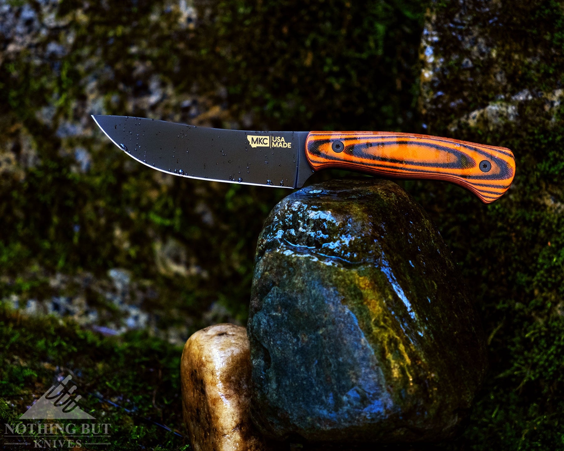 The Montana Knife Company Stonewall Skinner on top of a wet rock in front of a moss-covered granite wall. 