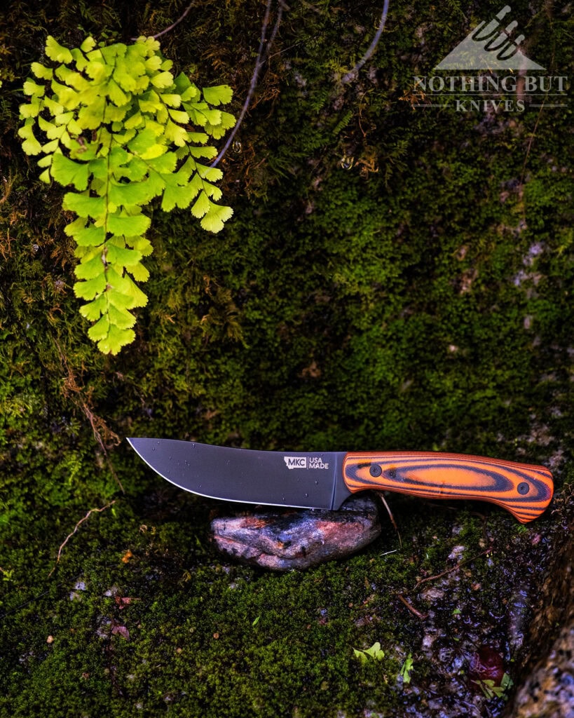The Montana Knife Company Stonewall Skinner fixed blade skinner balanced on a wet rock in front of a moss-covered granite wall.