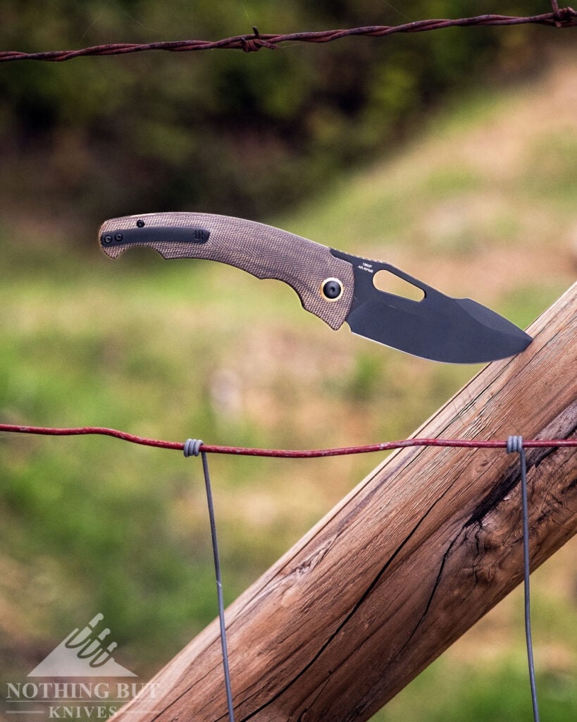 The Artisan Xcellerator on a ranch fence in front of a green field. 