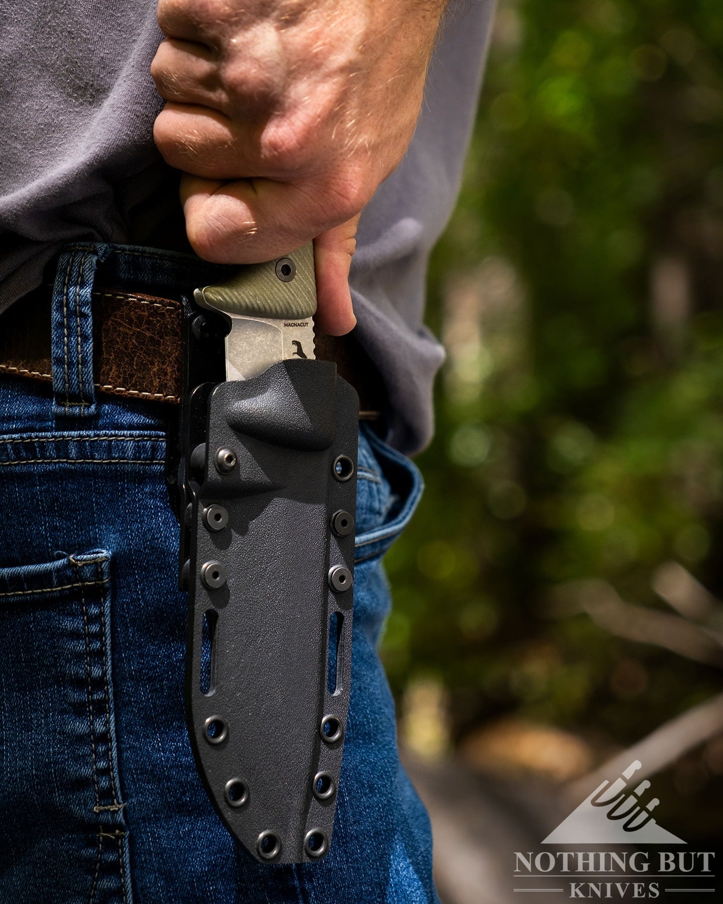 The Reiff Vicon being de4ployed from its kydex sheath which is hanging on a brown leather belt on the right side of a person's hip. 