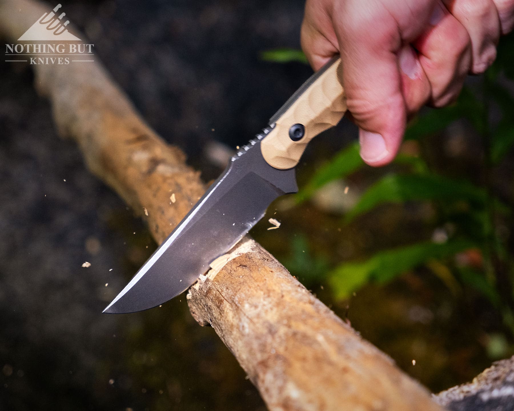 Toor Knives Brauler Review - Image 4 An overhead image of the Toor Brauler being used to chop a downed tree branch in the woods.