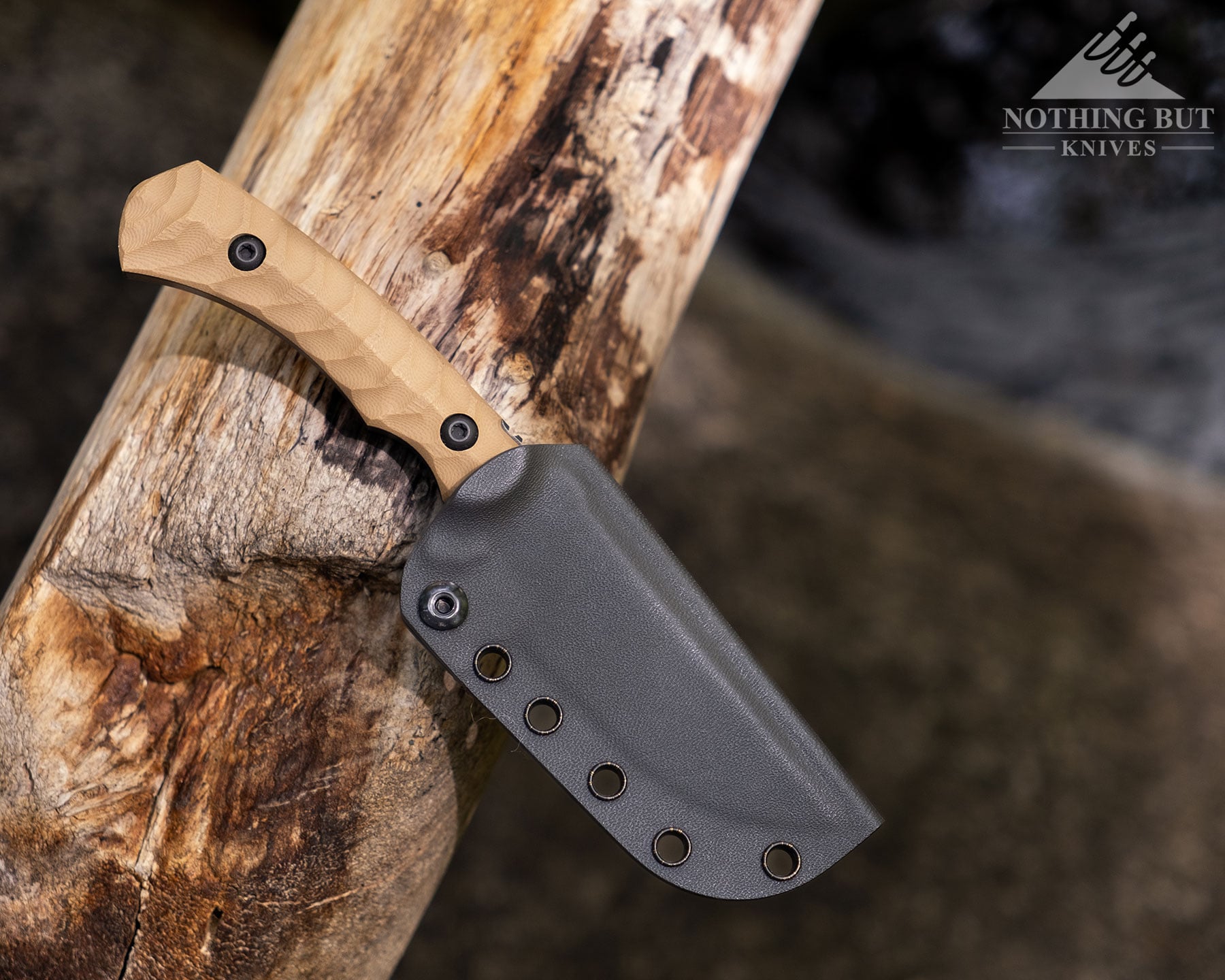 Toor Knives Brauler Review - Image 8 An overhead view of the Toor Brauler in its kydex sheath on top of a log above a mountain creek.