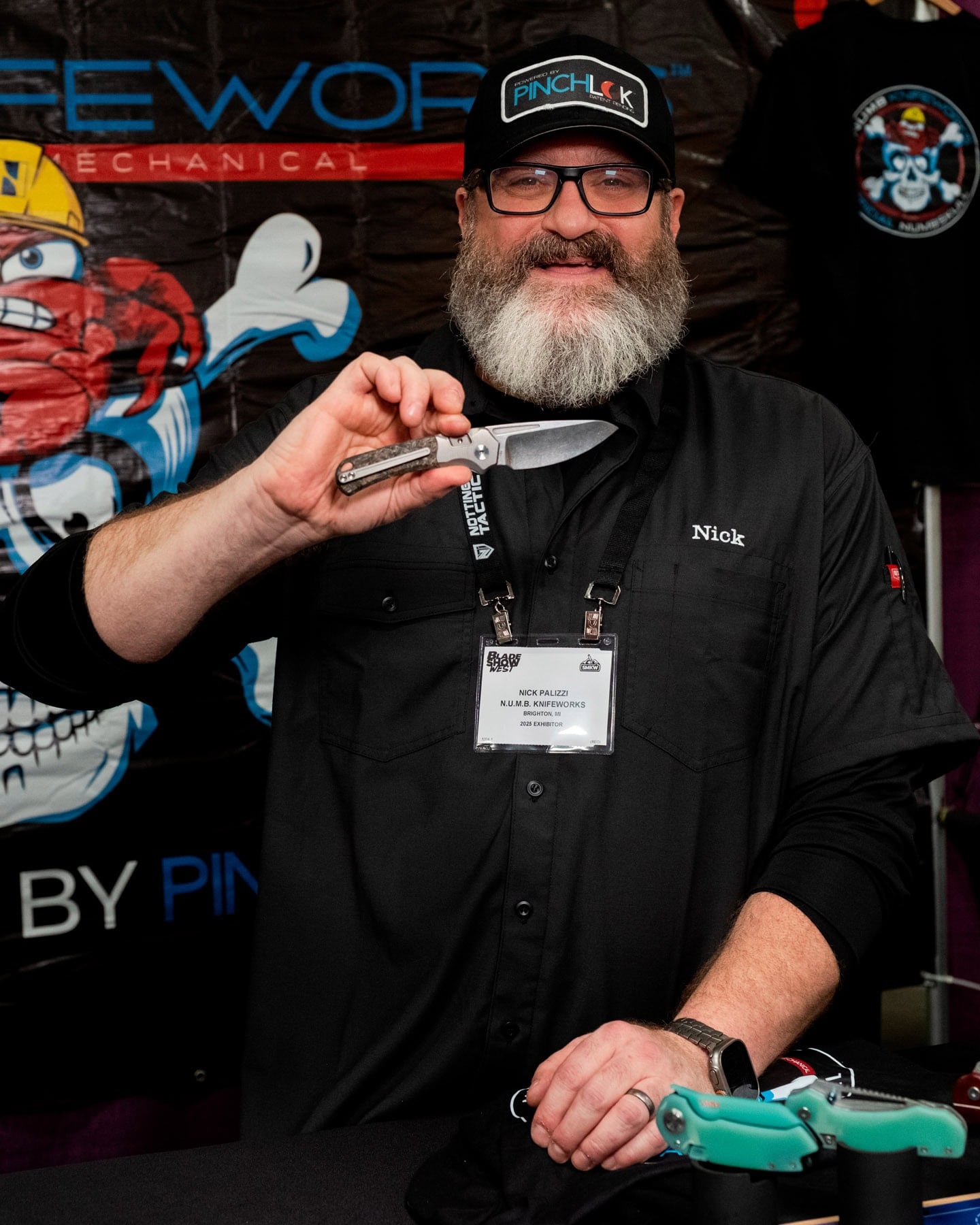 Blade Show West 2025 Wrap-Up - Image 5 Numb Knifworks founder holding a pocket knife that features his pinch lock.