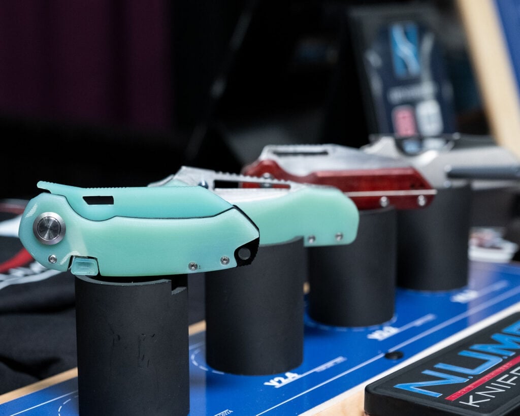 Blade Show West 2025 Wrap-Up - Image 6 Four Numb Knives prototypes on stands at Blade Show West 2025.