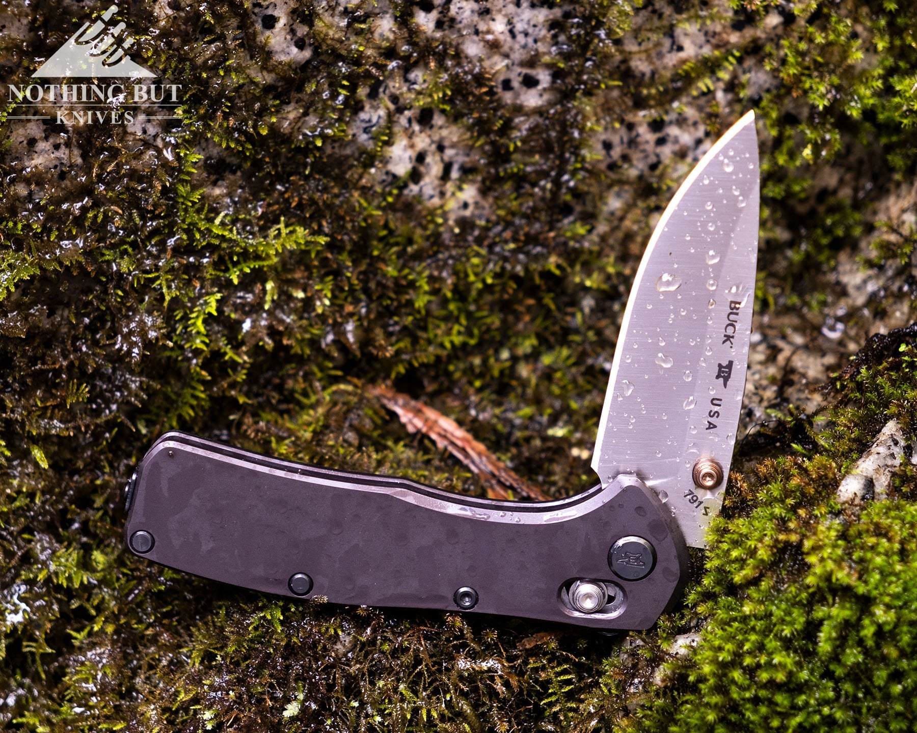 The Buck Range Elite  EDC knife with its blade in the half open position on a wet, moss-covered rock.