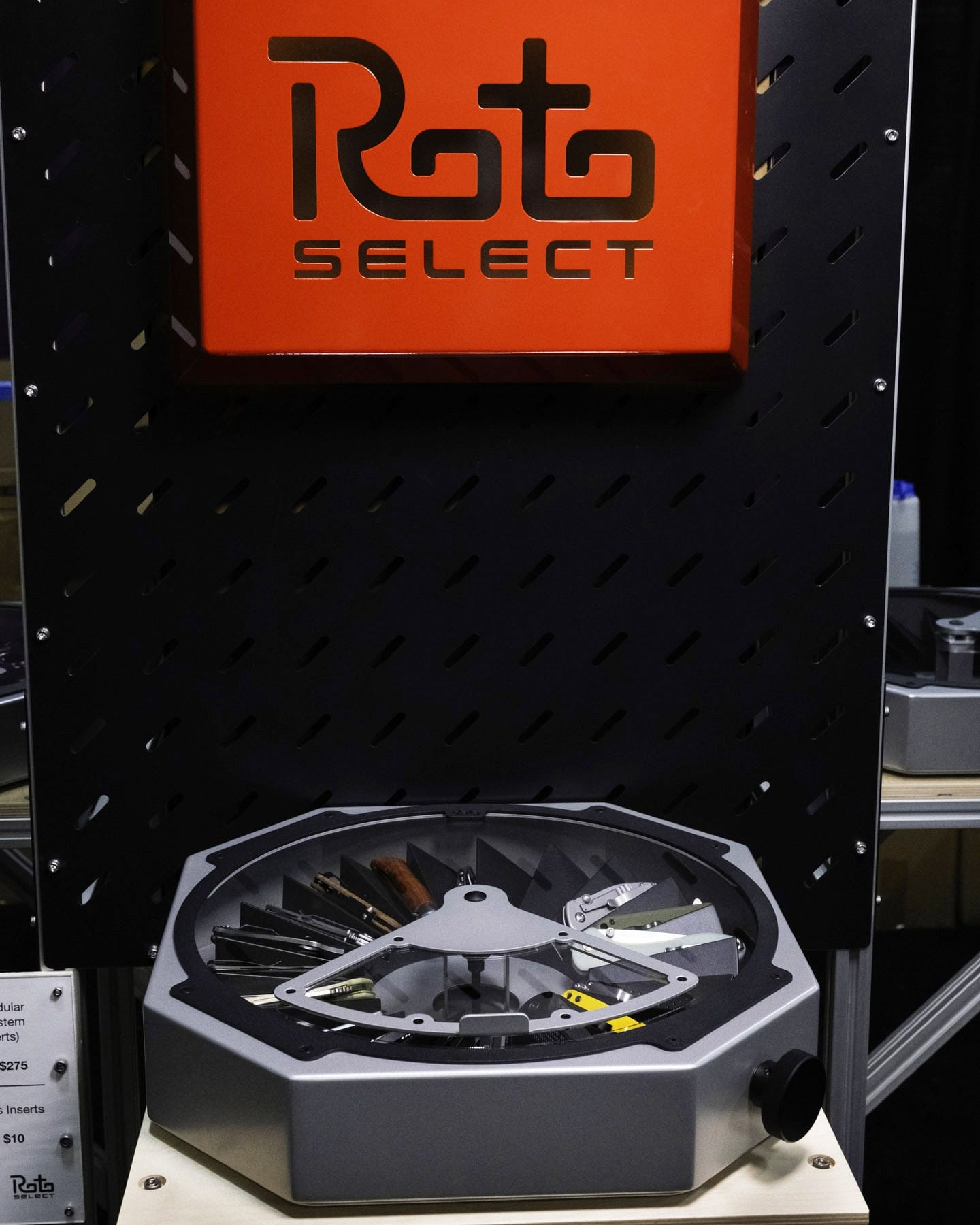 Blade Show West 2025 Wrap-Up - Image 12 The RotoSelect pocket knife organizer on a stand under the company logo at Blade Show West 2025.