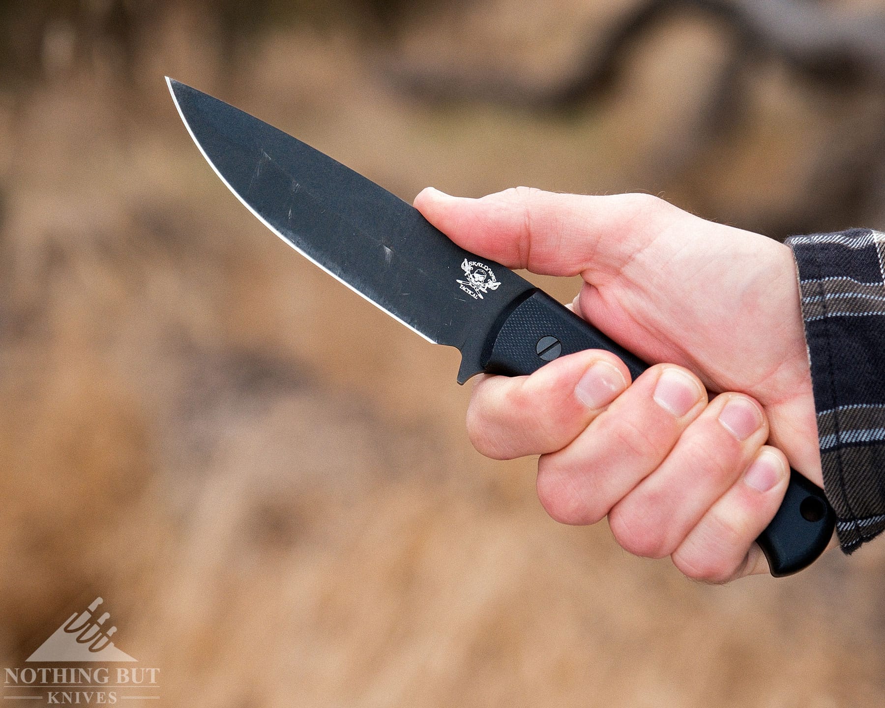 Skallywag Tactical. The Wanderer Review. - Image 7 A close-up of a person gripping the Skalleywag Tactical Wanderer bushcraft knife in their right hand with their thumb on the spine.