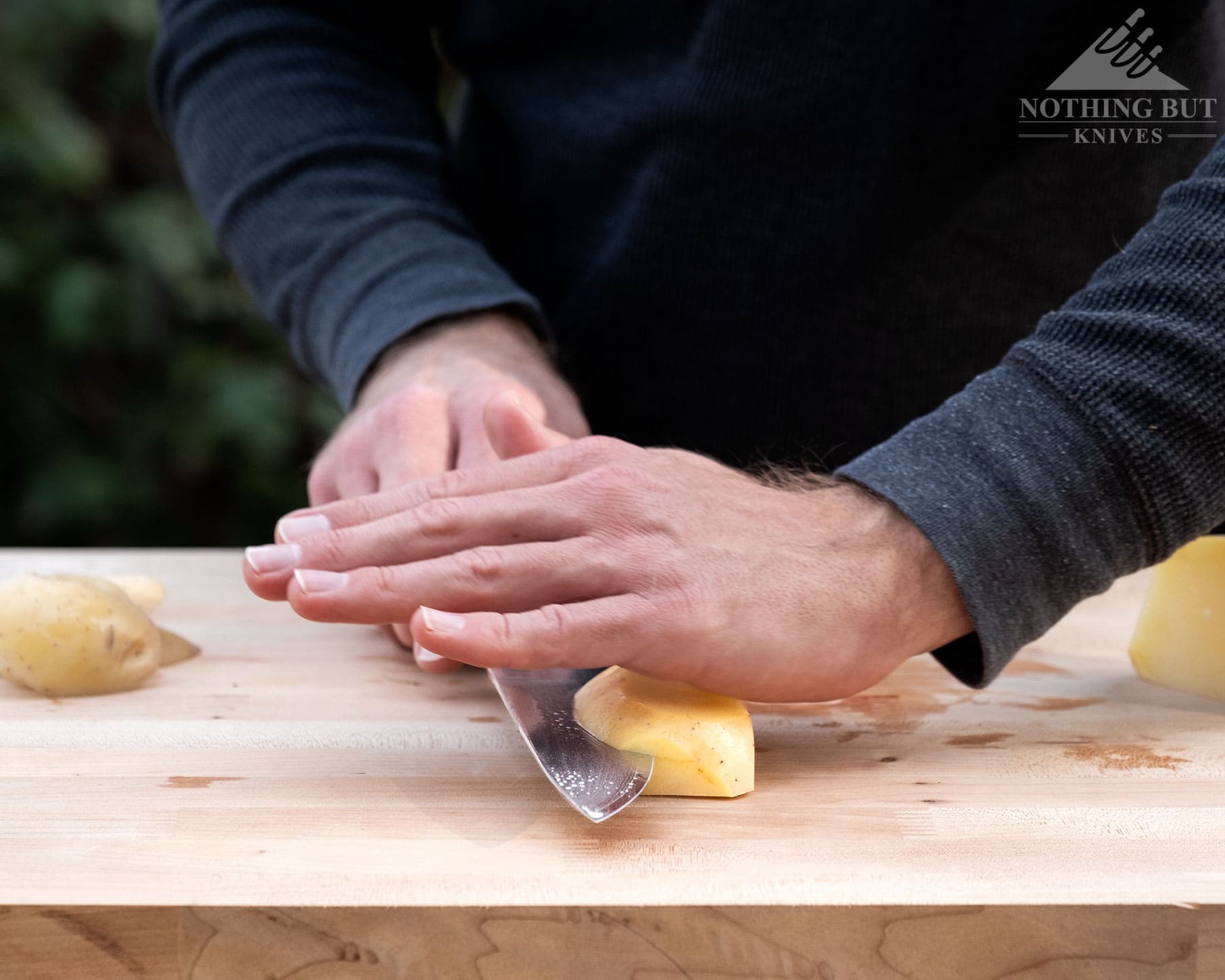Hexclad Chef Knife Review - Is It Just Marketing Hype? - Image 8 A close-up of the HexClad chef knife being used to sideways slice a potato.