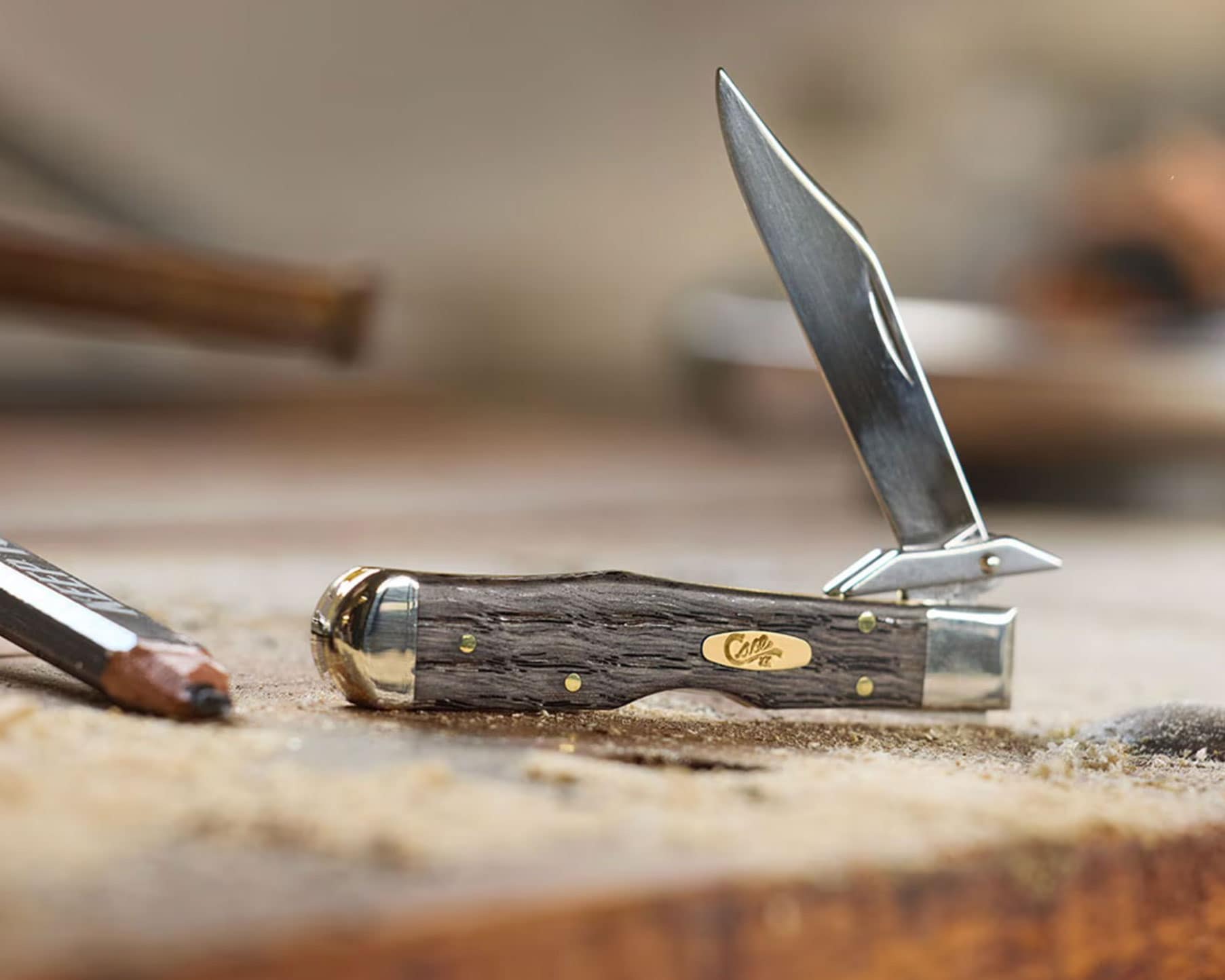 The Case Cheetah Cub slip joint knife with its blade in the half open position on a wood work bench. 